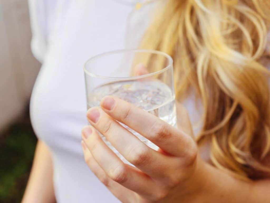 Mujer sostiene un vaso de agua de mineralización débil en una dieta para sop.