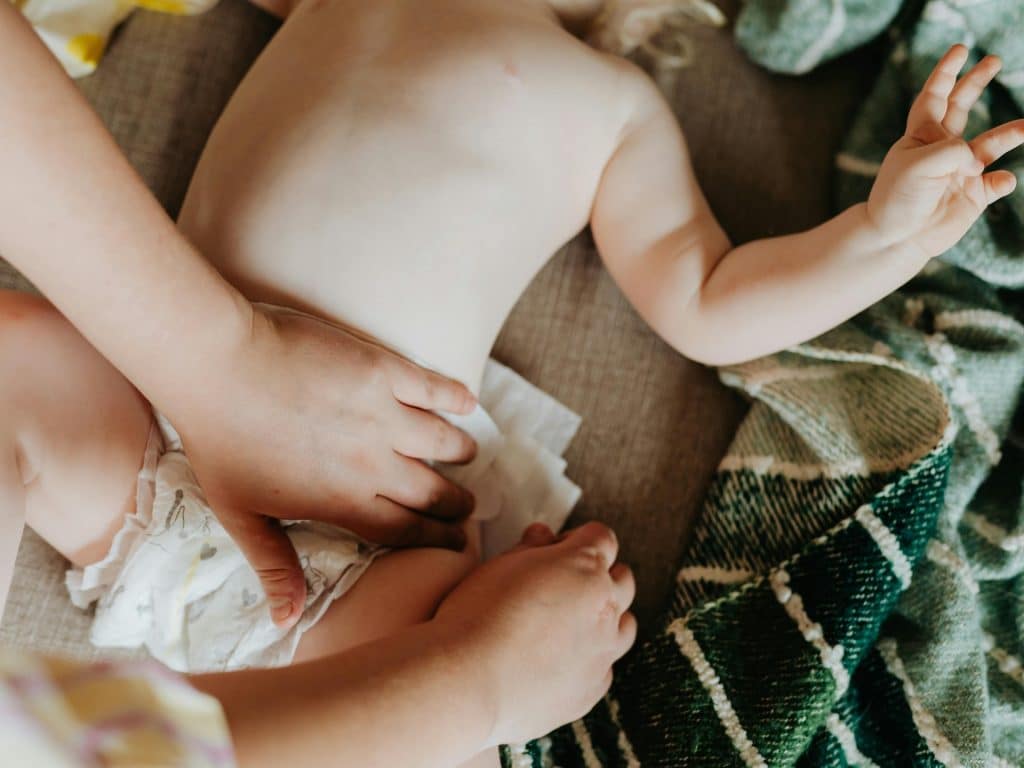 Madre realiza masaje abdominal a bebé con estreñimiento.