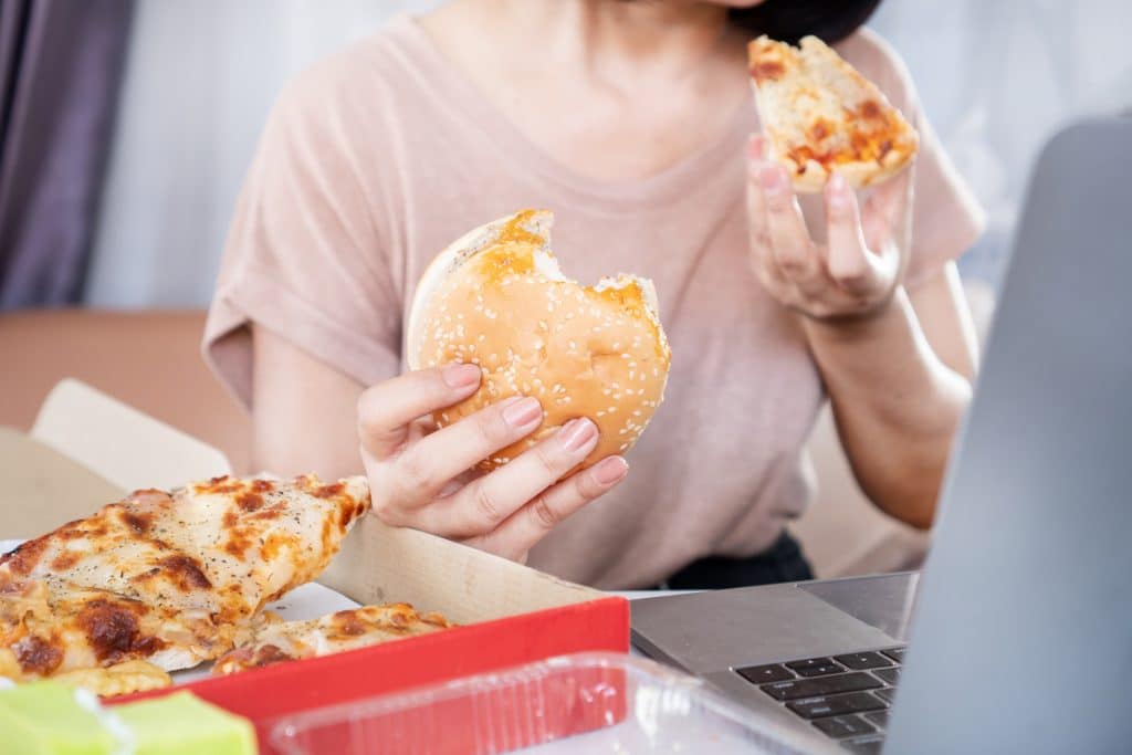 Mujer con bulimia come pizza y hamburguesa a la vez