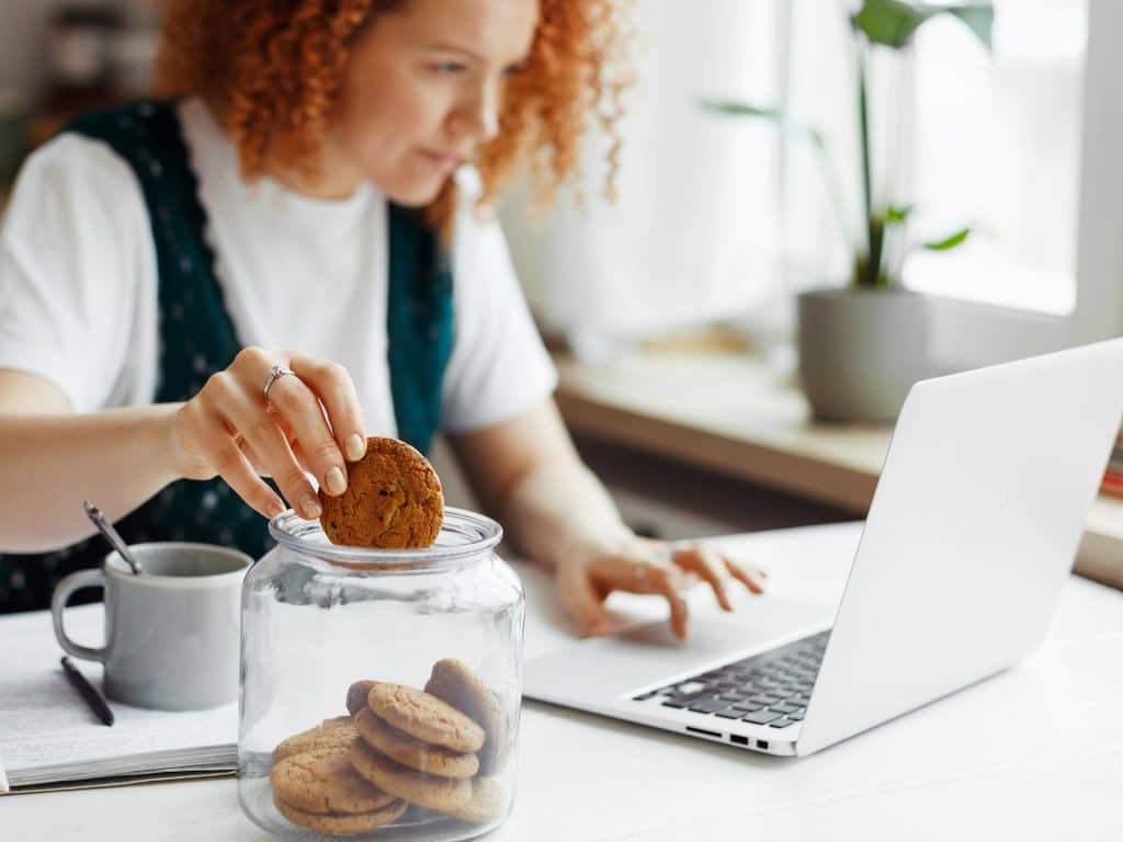 Chica trabajando y comiendo galletas