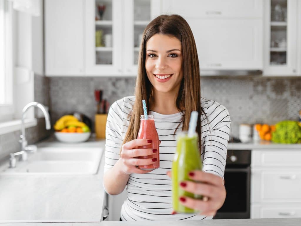 Mujer tomando dos batidos de frutas